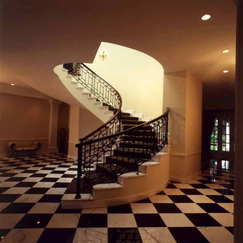 Escalera circular sobre piso cuadriculado de mármol negro y blanco en casa contemporánea de ciudad de Guatemala.