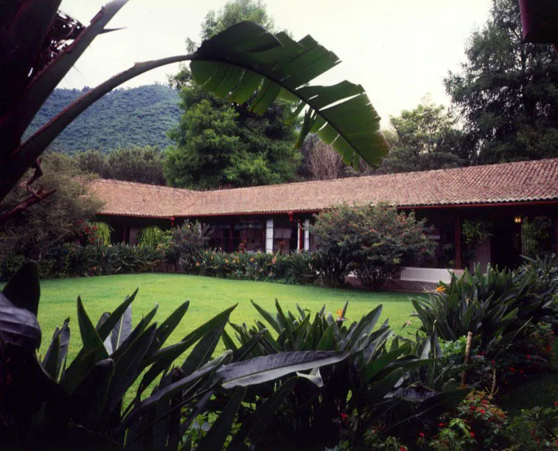 Casa patronal de una finca de caf en los alrededores de la ciudad de Antigua. Se trata de un tipo de casa similar al de otras fincas de la regin: una sola planta, jardn central enclaustrado, techo de teja de barro, largas galeras con corredores abiertos al espacio interior, en este caso un bonito jardn con csped y flores. Las habitaciones abren sus ventanas hacia las plantaciones. 