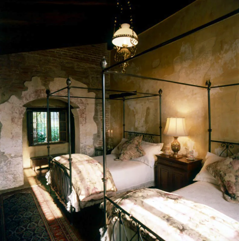Otro dormitorio de la casa, con camas de hierro forjado, fabricadas por artesanos locales, en Antigua. Toda la construcción es nueva, pero se le ha incorporado el repello en cierta áreas, como alrededor del arco, para dar un ambiente antiguo.