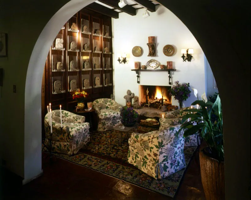 Pequeña sala contemporánea donde se aprecia,sobre la pared de la izquierda, el espacio diseñado para exhibir la colección de hachas prehispánicas de piedra, pertenecientes a la cultura maya. Sobre la chimenea, piezas de mayólica antigüeña y vasijas también de origen maya.