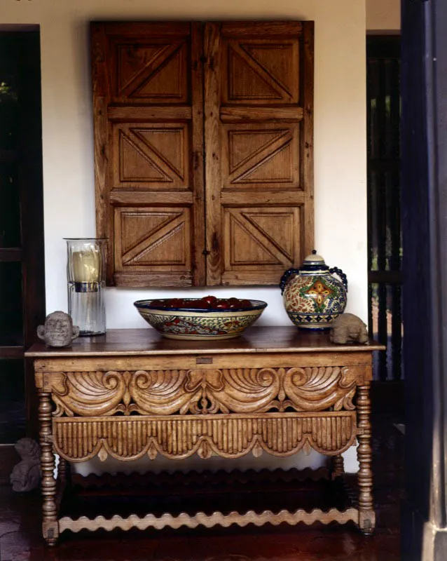Detalle de puertas talladas en cedro, de tradición guatemalteca, colocadas sobre la mesa antigua que exhibe adornos de cerámica mexicanos.
