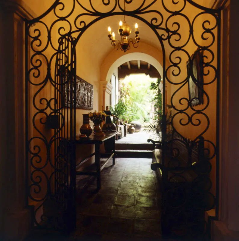 Entrada principal de la casa con reja de diseño contemporáneo. El pasillo, que conduce al patio, está decorado
con un gran relieve de madera primitivo sobre una mesa rústica.