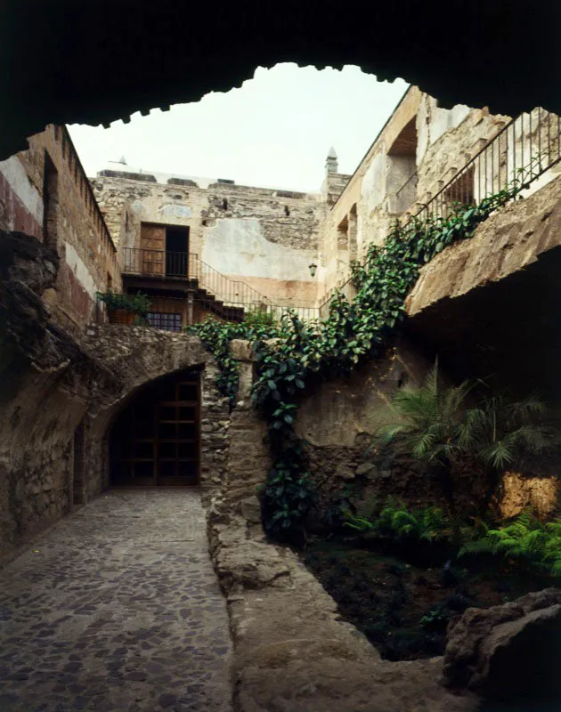 Vista de un área en proceso de reconstrucción, parcialmente jardinizada, que forma parte de una casa antigüeña del siglo XVIII, destruida por el terremoto. Se aprecian los muros originales de acceso a una habitación.