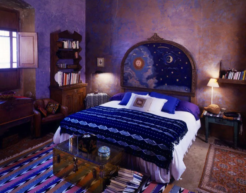 Dormitorio con cama de espaldar tallado en madera policromada. Alfombra contemporánea hecha a mano con motivos de jaspe y cubrecama de textil indígena. Ventana de postigo, con base acondicionada como asiento.