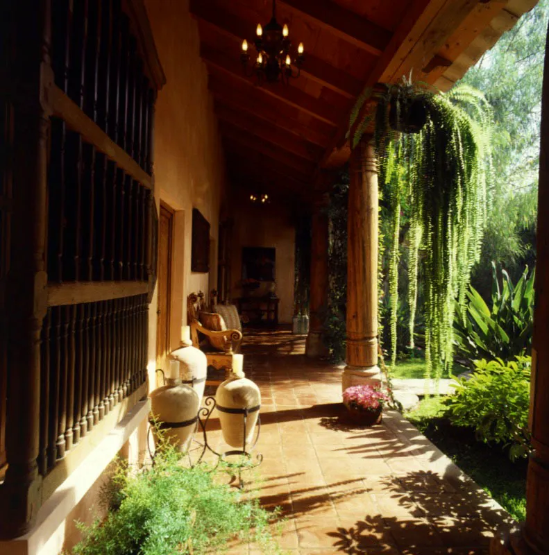 Corredor interior en forma de U que rodea el patio y da acceso a todas las habitaciones, amueblado con nforas de barro y muebles coloniales. 