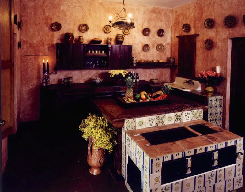 Cocina contemporánea forrada de azulejos de tipo colonial, con mobiliario rústico en madera y cerámicas de la época colonial, de la casa Montiel de Antigua, sobre la pared del fondo.