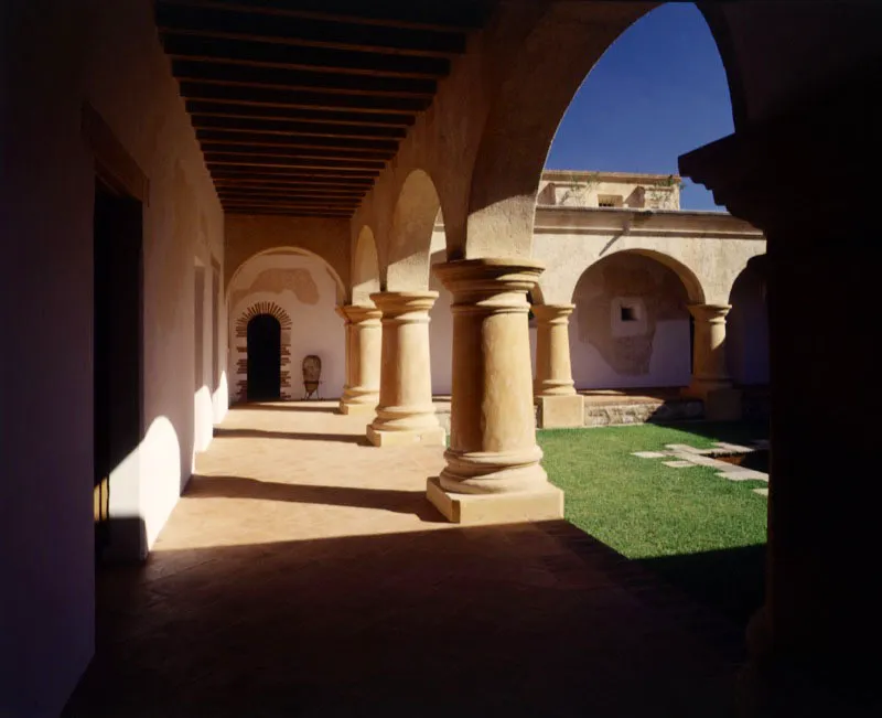 Ángulo del patio que muestra el mismo tipo de columnas cilíndricas que los claustros del convento y los arcos de medio punto. Al fondo del corredor, el arco que comunica este espacio con otras habitaciones de la casa.