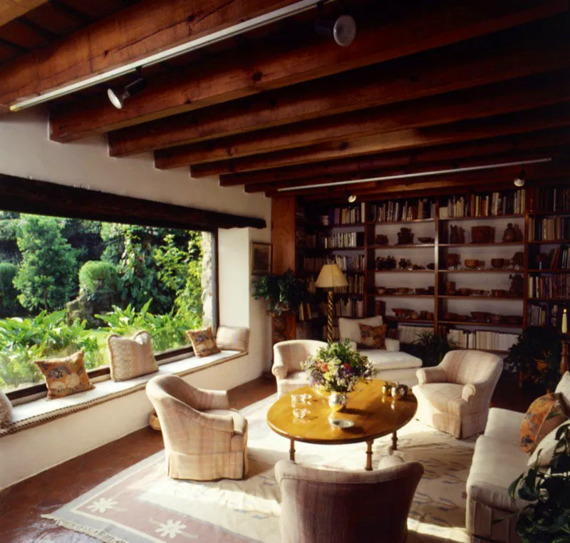 Sala de la misma casa, que se abre al jardín a través de una amplia ventana de vidrio; el interior,
de tonos claros, es de gran luminosidad. Las libreras con piezas mayas, la baldosa de barro y los muebles contemporáneos complementan el ambiente.