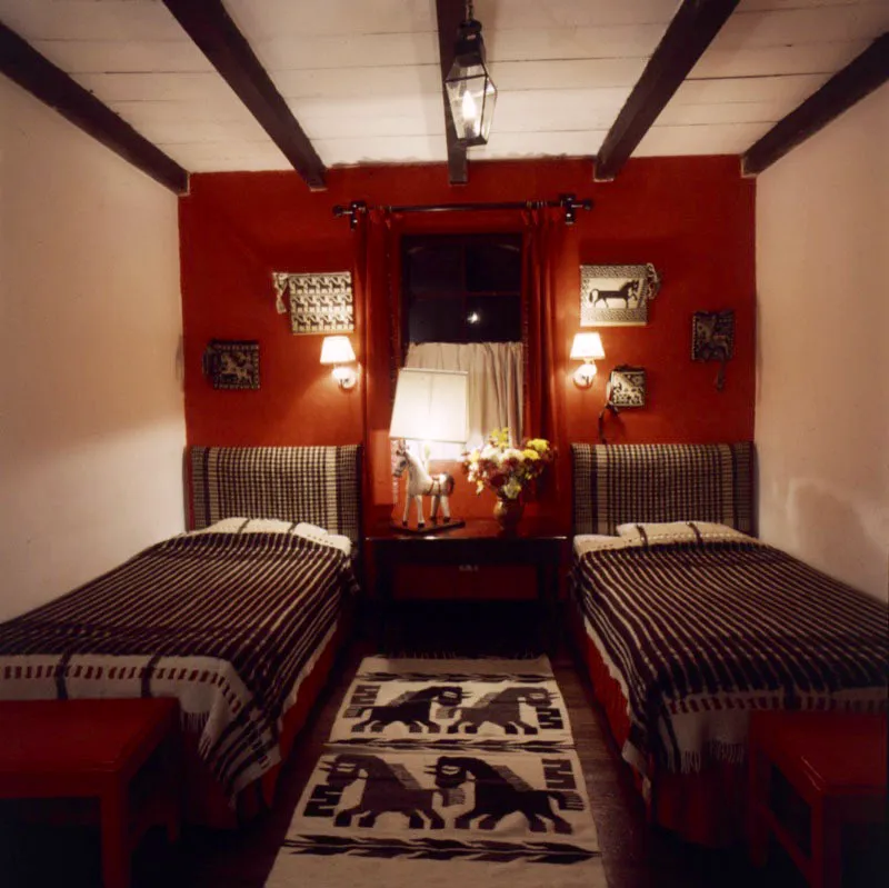 En las habitaciones, la decoración combina el color contrastante de las paredes con los cubrecamas y la alfombra, de artesanía en lana realizada en el área de Momostenango, Totonicapán, que se repite en los adornos de la pared roja del fondo; la base de la lámpara de mesa es un caballo artesanal de la región en madera pintada.