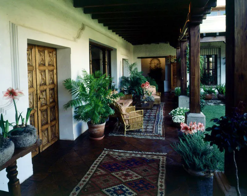 Casa restaurada en Antigua, que sigue la distribución y proporciones tradicionales. El corredor acondicionado
a los conceptos actuales de galería amueblada, lleva hacia un patio hecho jardín. Los muebles de caña son fabricados en Cobán por artesanos de la región. La puerta es de madera tallada al estilo tradicional. Al fondo, nicho con copete en forma de resplandor.