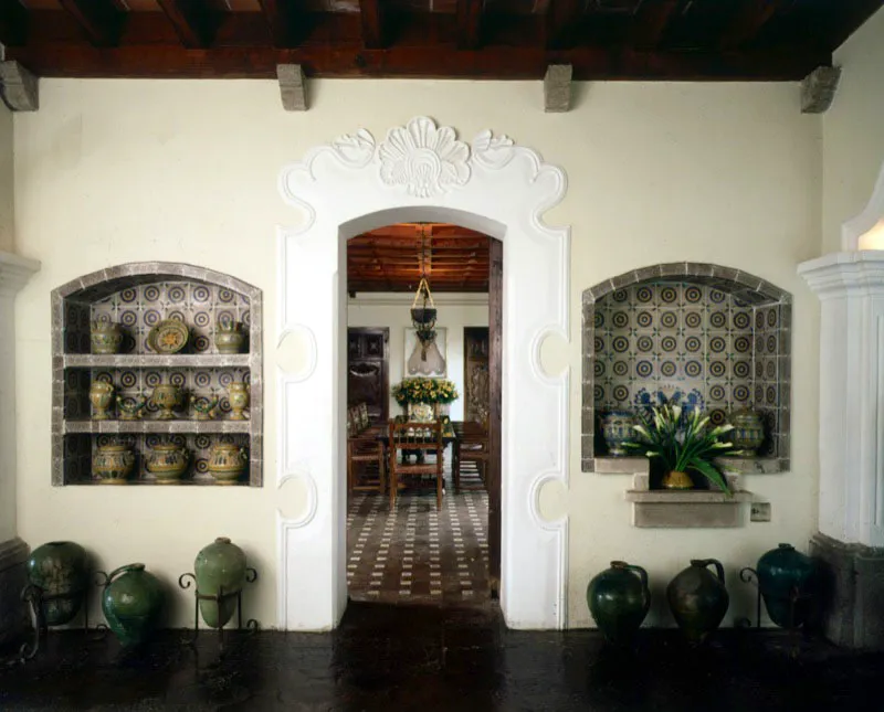 En primer plano, dos nichos con fondo de azulejos, en los que se han colocado piezas de mayólica local; en el suelo varios tipos de ánforas y garrafas españolas en barro cocido, utilizadas para la exportación de aceite y vino. A través del arco de la puerta, que tiene un marco trabajado en la técnica de ataurique, se puede ver el comedor.