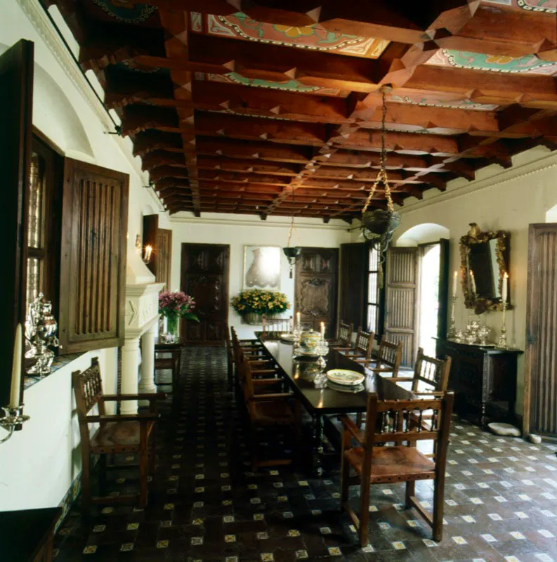 Gran comedor de carpintería sencilla, mesa, trinchante y sillas forradas en cuero. El piso es de baldosa con azulejos intercalados. Se aprecian las hojas de las ventanas de madera con un interesante trabajo de talla acanalada, el espejo sobre el trinchante y el artesonado. Al fondo, entre las puertas talladas, una casulla colonial enmarcada.