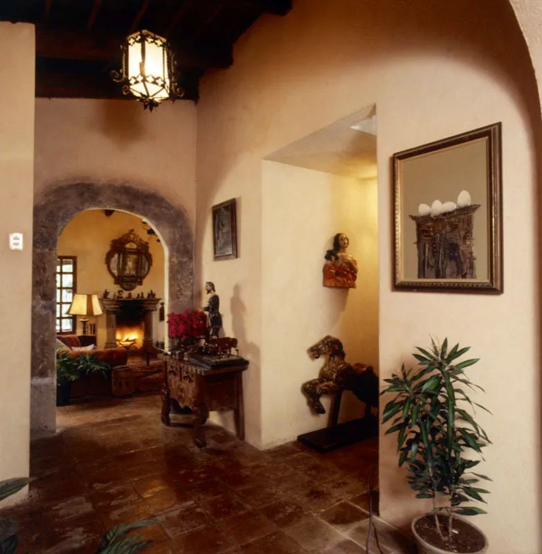 Vestbulo de la casa de campo anterior, desde el cual se accede al comedor y a la sala principal a travs de un arco de piedra empotrado. Sobre la mesa,  una talla de San Jos. En el corredor, a la derecha, una  figura colonial de un nima  del purgatorio, debajo de la cual hay un caballo en madera de carrusel de pueblo. A la derecha, una pintura del artista salvadoreo Roberto Hueso. 