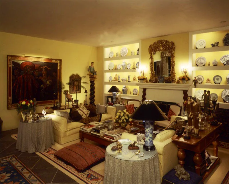 Sala de una casa contemporánea de la ciudad de Guatemala, en la que llaman la atención los objetos decorativos que forman un ambiente de variedad barroca. A la izquierda, un gran cuadro del pintor yugoslavo Kristian Krékovic, en el que aparecen unos indígenas peruanos; al lado, un pequeño óleo colonial con marco barroco dorado, y en la esquina una columna salomónica en negro y oro con una escultura antigua articulada sentada encima. La pared del fondo está dividida en dos por una chimenea, sobre la que hay un gran espejo artesanal en pan de oro y a ambos lados estanterías con piezas de cerámica azul y blanca, intercaladas con figurillas prehispánicas. El amueblado destaca cojines multicolores. En las distintas mesas, multitud de pequeños objetos: esculturas, orfebrería, y en la mesa central varios libros.