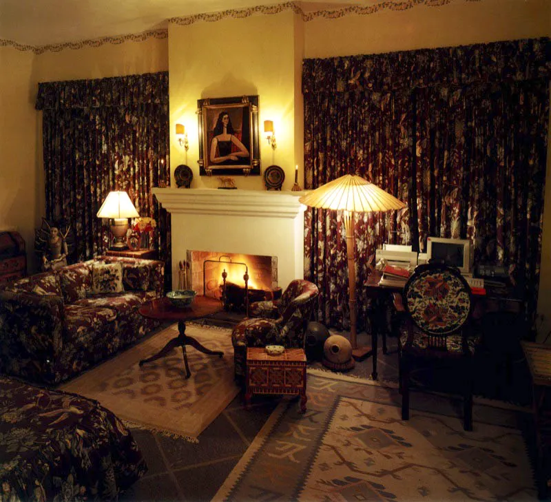 Dormitorio con estar, cuyo elemento dominante es la tapicería de los muebles y los cortinajes, que contrastan con el amarillo de los muros. El piso es de adoquines en granito gris, con alfombras dhurry de la India. Sobre la chimenea, una pintura del artista guatemalteco Miguel Ángel Pérez y dos platos de mayólica del país.