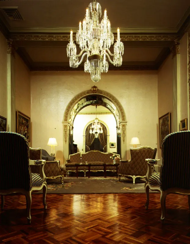 El sobrio decorado, las lámparas chandelier, el piso de parqué y la alfombra oriental embellecen la sala de la residencia privada.