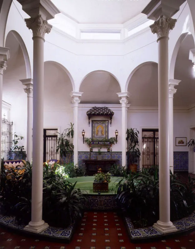 Tanto el comedor como la sala de estar dan a este patio interior. Remodelado en 1927, los azulejos, pintados a mano, fueron trados de Valencia y Sevilla; las rejas de hierro forjado vinieron de Toledo. En 1955, la bveda de vidrio del techo fue cubierta por razones prcticas, pero igual entra mucha luz natural por los costados este y sudeste. Las columnas de hierro fundido soportan los arcos de linterna, crendose en el interior una glorieta que remata, en el medio, con una fuente. Al fondo, el mosaico de Nuestra Seora de los Reyes agrega un toque tpico espaol. Antonio Castaeda Buraglia