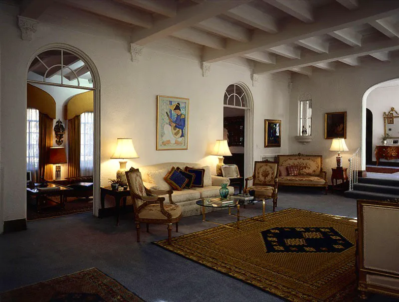 Sobre el sofá del Gran Salón, pintura de maestro Jalel Ben Abdallah (1921- ), uno de
los miembros fundadores del movimiento artístico “Escuela de Túnez”. El centro de atención de la habitación es la magnífica alfombra en tonos azul y dorado, anudada a mano y clásico diseño Kairouan. El nombre corresponde al de la ciudad santa situada a 160 kilómetros de la capital Túnez, que fue, a su vez, capital del país durante la dinastía Aghlabite (800-900 d. C.) y el más importante centro cultural, intelectual y espiritual del Mediterráneo. Todavía hoy es sede de las valiosas alfombras.
Antonio Castañeda Buraglia