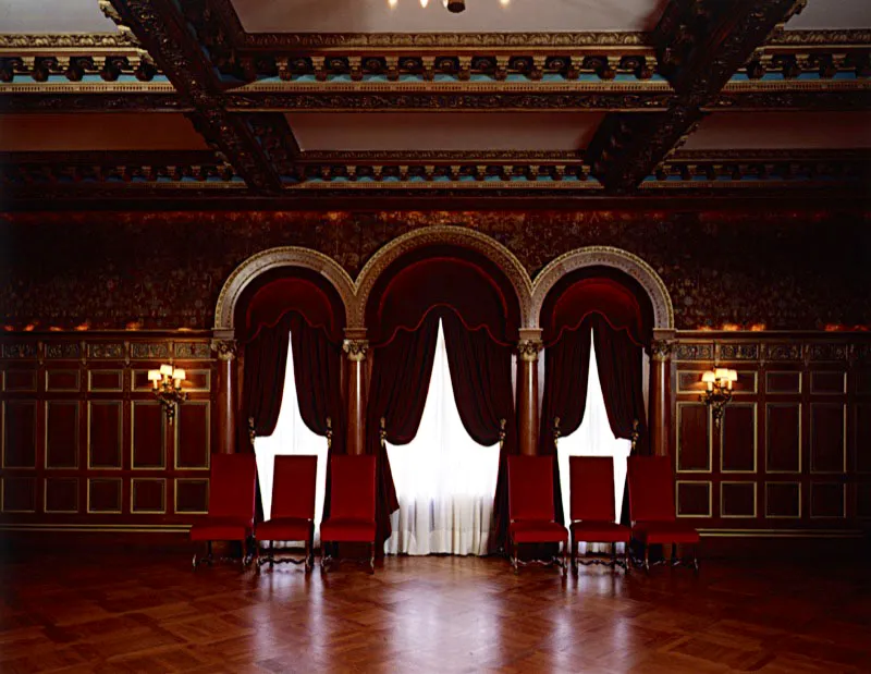 La parte superior de las paredes del salón de baile está recubierta con paneles de damasco en tonos granate y oro. Los nueve paneles del techo están separados por magníficas vigas, talladas y recubiertas con esmalte azul verdoso y oro. Las cortinas de terciopelo rojo completan la magnificencia del salón. Antonio Castañeda Buraglia