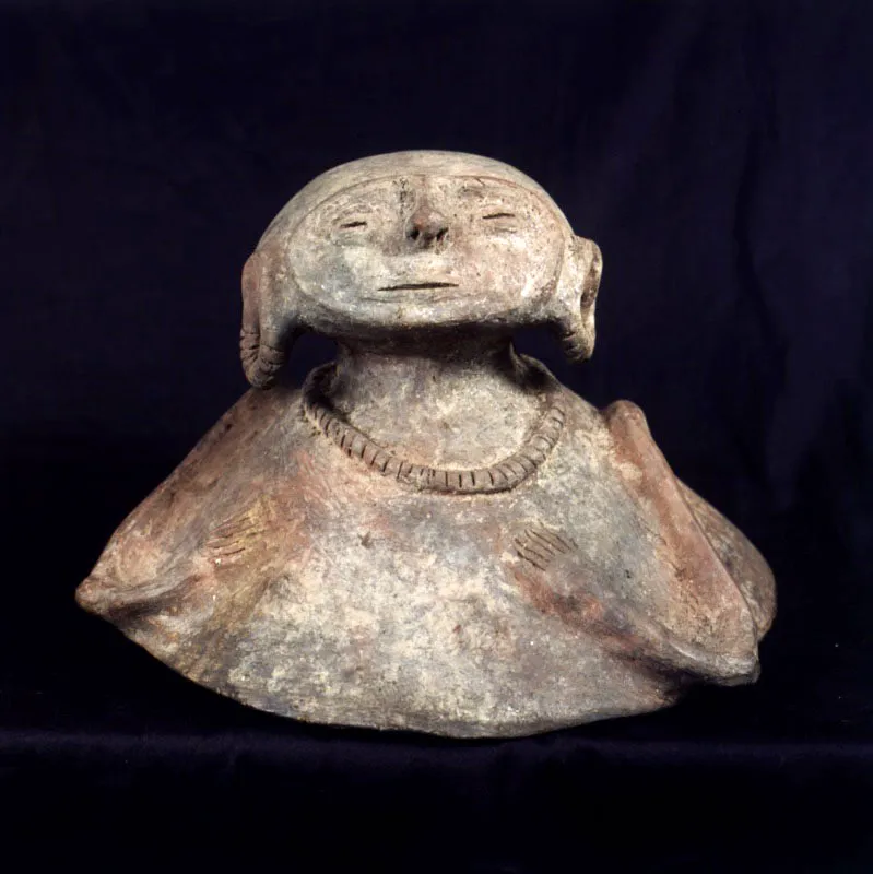 Cultura Sinú. Tapa de urna.
Cerámica, 25 cm de diámetro x 18 cm
La cuenca del río Sinú, junto con la depresión momposina, conformaba en la época prehispánica un mismo territorio definido como cacicazgo. El uso reiterativo de imágenes femeninas en la cerámica tiene una estrecha relación con la tradición matriarcal. Con miras a fortalecer la diferenciación social y a justificar la ocupación de los campos elevados por sus descendientes, los fundadores de linajes eran representados en arcilla para funciones alimenticias u ofrendatarias, que se diferencian únicamente en el uso de tapas para el caso de los ritos funerarios. En cuanto a los utensilios de carácter utilitario, de cuya producción estaban excluidas las alcarrazas, por lo general contenían los alimentos para las funciones de tipo alimentario u ofrendatario, diferenciadas únicamente en cuanto al uso de tapas para el caso de los ritos funerarios. Esta vasija evidencia un particular intercambio cultural en el uso de ojos en forma de grano de café, representación característica de la cultura tairona.