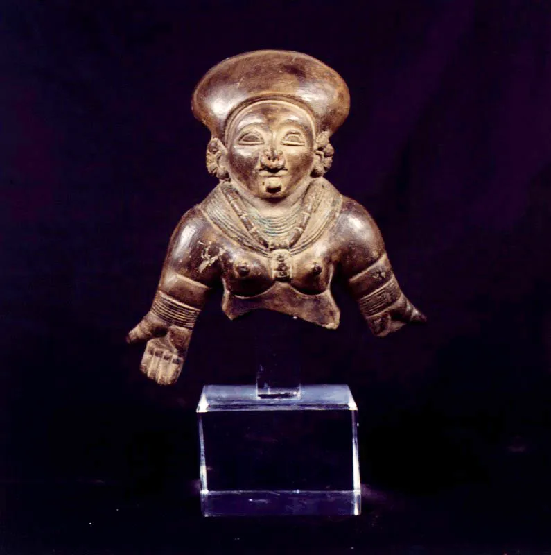 Cultura Quimbaya. Figura antropomorfa.
17 x 15 x 8 cm

Se acostumbra designar como quimbaya (ca. 400 a. C.) a todos los objetos arqueolgicos encontrados en la zona ocupada actualmente por los departamentos colombianos de Caldas, Risaralda, Quindo y el sector nororiental del Valle del Cauca. 
La cermica quimbaya, proviene de la coccin de materiales como barro, arcilla y greda y posee rasgos caractersticos como el uso de lneas para representar los ojos, la preferencia por figurar animales pequeos y el uso exclusivo de figurillas antropomrficas del tipo tabloide como la de este caso. Se trata de la figura maciza y sedente de un cacique. Es probable que las perforaciones alrededor de la cabeza  hayan sido utilizadas para colocar penachos de plumas, como una corona a la usanza de la que llevaba el cacique original. La postura de su mano, con intencin de ofrendar, refuerza la idea de su uso ceremonial.
 