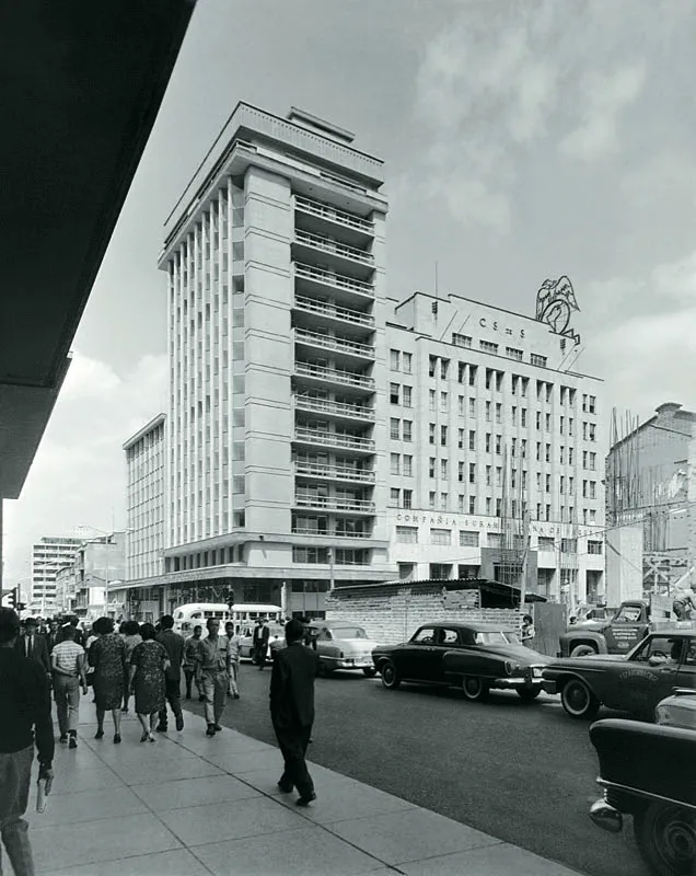 Sedes de Suramericana en la Carrera Carabobo entre Boyacá y Colombia, hacia 1963. Al primer edificio estilo art déco de 1945 (derecha), obra del arquitecto austriaco Federico Blodek y de Tulio Ospina Pérez y Carlos Gutiérrez, se le anexó, en 1961, la torre diseñada por Augusto González.
Fotografía de Diego García, Biblioteca Pública Piloto.