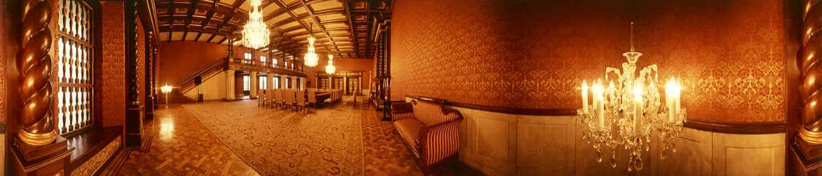 Salón Bolívar: tres arañas de cristal penden de un cielo raso en madera, dividido en casetones. Se aprecia un balcón sobre columnas salomónicas en piedra labrada con barandas de madera tallada. Completan la decoración dos sofás estilo imperio. Cristóbal von Rothkirch
