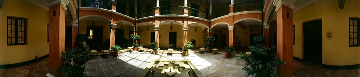 Patio central cubierto por marquesina, rodeado de arcos “carpanel” apoyados en columnas cuadradas y con piso de piedra original. Colindante con el Teatro Colón, sus habitaciones estan distribuidas en lo que una vez fueran una casa republicana y una colonial. Cristóbal von Rothkirch