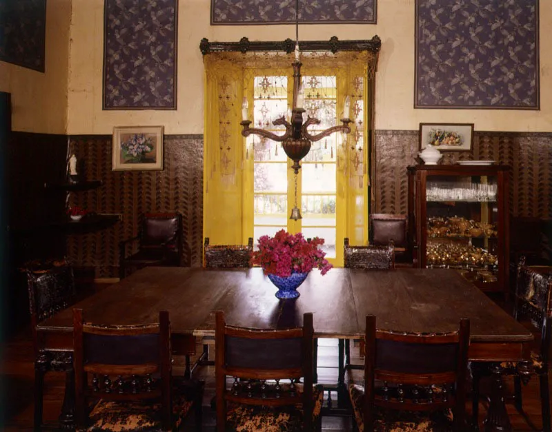 Simijaca, Cundinamarca.
La decoración y amoblamiento ecléctico, incluyendo objetos y acabados del siglo xix en una casa que, a juzgar por sus dimensiones espaciales, data de época colonial. Nótese el uso de papel de colgadura en paneles murales individualizados. La escena podría pertenecer también a una casa en el barrio de La Candelaria en Bogotá.