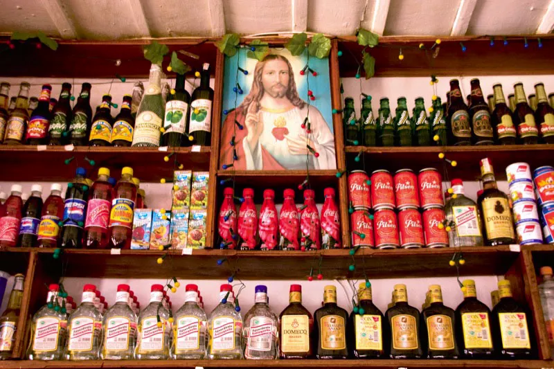 Estantería de una tienda de Jardín en la que se exhiben diversas bebidas y el popular cuadro del Sagrado Corazón de Jesús. Carlos Pineda