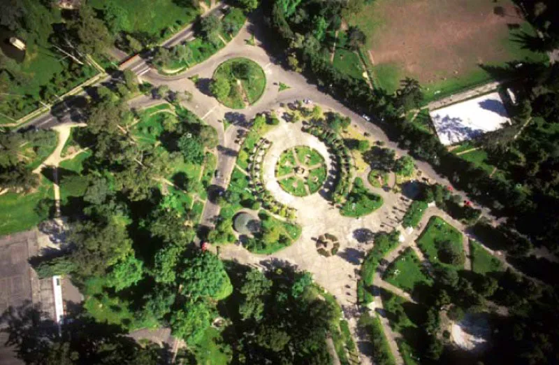 Parque Nacional Enrique Olaya Herrera, Bogotá.
Fue inaugurado por este mandatario en 1934. Su parte urbana asemeja un triángulo redondeado —del que observamos la cúspide— en la que entre caminos, monumentos y piletas están el reloj donado por la comunidad suiza, hacia 1954, la pérgola y fuente y, a la derecha, la cancha de jockey.