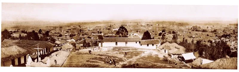 Vista panorámica de Bogotá en 1895. Barrios de Egipto y Belén. La fotografía parece haber sido tomada desde la iglesia de Egipto y puede verse la actitud expectante y curiosa de los vecinos, que miran hacia arriba como pendientes de la cámara. Estos barrios orientales de la ciudad no tenían problema para el abastecimiento de agua, de la que se proveían en las numerosas quebradas que bajan de la montaña, y que, muy disminuidas en número, son hoy zona de reserva del acueducto de Bogotá. Foto de Henry Duperly.