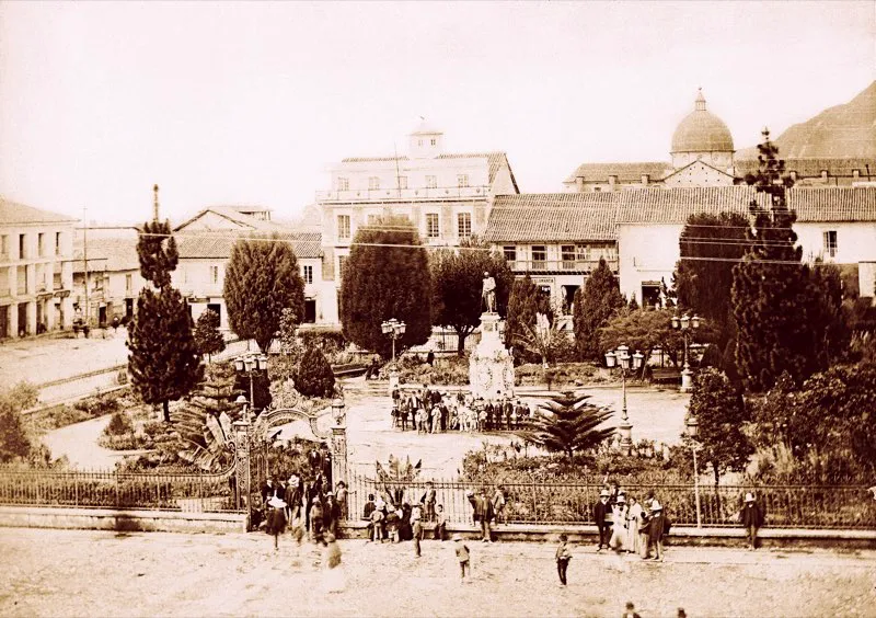  Uno de los trabajos emprendidos por el presidente Rafael Nez desde 1881 fue la remodelacin de la Plaza de Bolvar y su entorno. Para 1894 era, sin discusin, la ms bella de la ciudad. El historiador Lismaco Palau la describe as: En el centro de ella se levanta la famosa estatua del Libertador Simn Bolvar, fundida en bronce, obra del genio del famoso escultor italiano Pietro Tenerani, donada a Bogot por el seor Jos Pars. El pedestal fue reconstruido en el ao de 1879 por el seor Mario Lombardi, de orden del Secretario [ministro] de Obras Pblicas, doctor Emigdio Palau, en la administracin del general Julin Trujillo. Este pedestal es de piedra y de mrmol, con relieves de bronce que representan varios pasajes alusivos a la vida del Libertador; est adornado, adems, con los cinco escudos de armas de Colombia, Venezuela, Ecuador, Per y Bolivia. El parque tiene bellsimos rboles, dos pilas de bronce, varios asientos de madera y est rodeado de una hermosa verja de hierro con su respectiva portada. En ella se da retreta los jueves. En la foto de Henry Duperly (1894) se ve el costado norte de la plaza, con el Hotel Sucre. En la esquina suroriental de la calle 11, un detalle del edificio de las Galeras, donde estaba desde 1888 la torre de la Compaa de Telfonos de Bogot, que ardera, con todo el edificio, seis aos despus. 