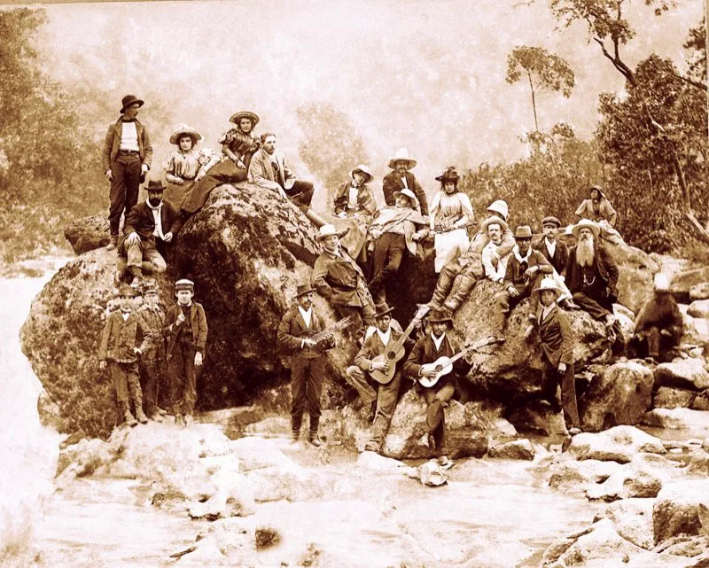 Un grupo de paseantes, con guitarras y tiples, ha tomado puesto privilegiado para presenciar la hazaña del equilibrista estadounidense Harry Warner el 16 de noviembre de 1895: “Desde ayer está lleno de gente el camino de Soacha porque todos se han ido a presenciar el arriesgado paso por encima de la catarata del Tequendama que debe efectuar hoy a las once del día el señor Harry Warner. Los carruajes que hay en la ciudad están tomados, muchos van en bicicleta, muchísimos a caballo y una legión a pie. La ciudad se quedó sola”, informa el diario El Telegrama. Fotografía de Alfredo Esperón.