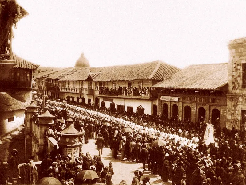 Espléndida fotografía de la procesión del Corpus en 1895, tomada desde el extremo nororiental del puente de San Francisco. La procesión desfila por la carrera 7.ª, comienza a atravesar el puente y llega a la calle 15. Al fondo sobresale la cúpula de la iglesia de Santo Domingo.