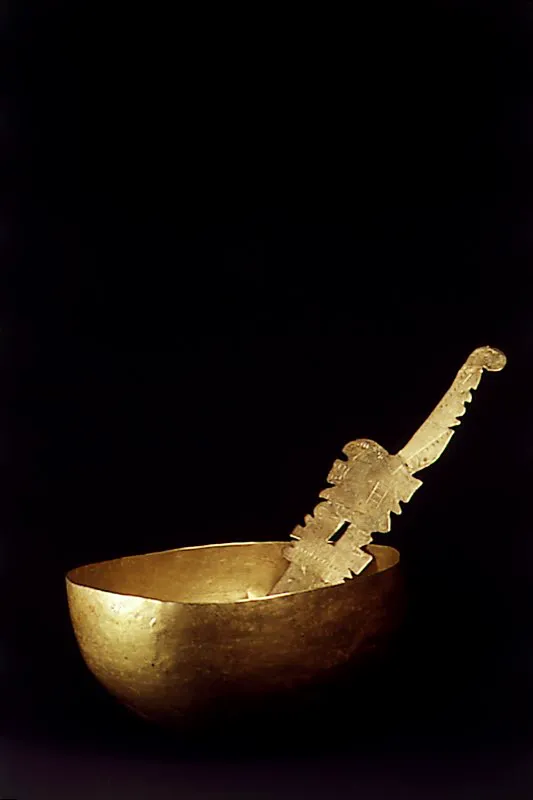 Taza ceremonial y cuchara prehispánica, en oro, con mango martillado y decorado. El recipiente en forma de totumo está elaborado con la técnica del martillado. El cronista J. Robledo registró el uso de estos objetos por los aborígenes, al escribir que: “…beben con vasos de oro,…tienen sus cucharas de oro y vasijas”. S. XI d. C. Cultura Quimbaya. La cuchara, que pertenece a la cultura Calima, es de la misma época. José Fernando Machado