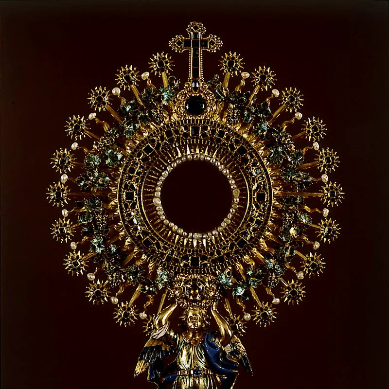 Detalle de custodia en oro con prolija incrustación de piedras preciosas. La orfebrería y la platería en la época colonial tuvieron un amplio desarrollo en el ámbito religioso. Gran fastuosidad y riqueza se acogió y se propagó para el culto de la Iglesia. Esta custodia quizás sea uno de los más bellos ejemplares, salidos de las manos de los maestros de la orfebrería eclesiástica, elaborados en el país durante el siglo XVIII. Se le dio el nombre de La Lechuga, por la dominante tonalidad verde, dada por las 1.435 incrustaciones de esmeraldas que posee. Piedras salidas de las minas de Muzo, Coscuez, Chivor y Somondoco, que existían desde los tiempos prehispánicos y cuya fama las señala como las de mayor pureza y el más hermoso color verde del mundo. La parte superior, con forma de sol, está sostenida por un mástil, réplica de la imagen de un ángel. Bogotá. Óscar Monsalve