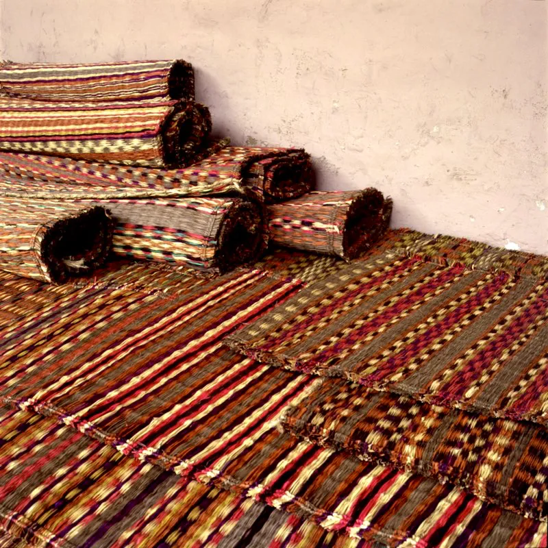 Conjunto de esteras tejidas en fibras de palma sobre pita. Para su elaboración se utilizan hojas jóvenes que se desflecan, se cuelgan y se ponen a secar y a blanquear al sol. Tradicionalmente se teñían con achiote. Se usan para cubrir los pisos. Ovejas, Sucre. José Fernando Machado