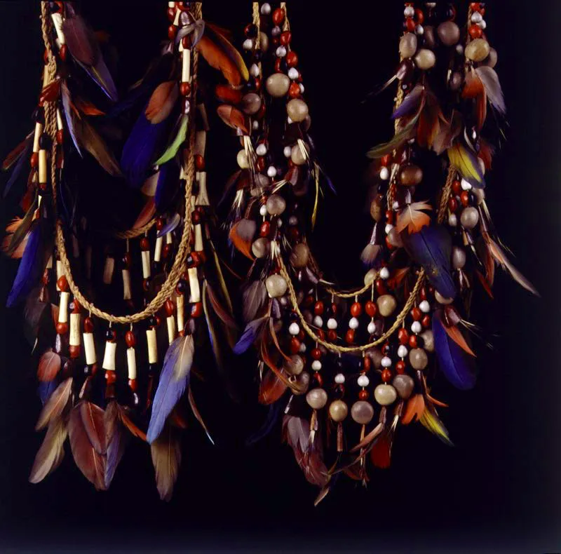 Collares ceremoniales en plumas de guacamayo y loro, con semillas ojos de dios o lgrimas de San Pedro, pepas rojas de siringa, ojo de mueco de color negro, segmentos de hueso y chaquiras, atadas a una fibra vegetal. Vaups. Pilar Gmez
