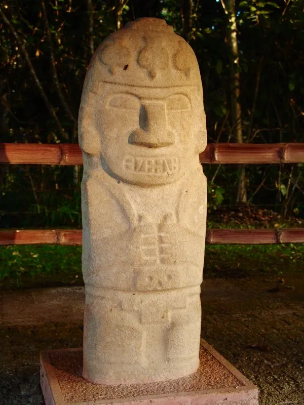Estatua hallada en la Mesita B del Parque Arqueológico de San Agustín, que ilustra el hecho fundamental del lenguaje artístico del Macizo Colombiano: en su gran mayoría las estatuas tienen forma fálica. Vistas de frente, repiten el mismo esquema: cabeza parabólica sobre un cuerpo cilíndrico macizo, con los brazos pegados al cuerpo, y un corte que simultáneamente distingue el glande y la cabeza del personaje.