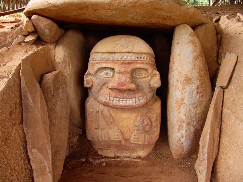 Estatua de un personaje con un palillo y un niño en las manos, descubierta en el alto de El Purutal. La detallada pintura del rostro muestra los ojos rodeados de amarillo, con los párpados pintados de negro. Un campo rojo resalta el filo de la nariz, se extiende por los arcos superciliares rodeando el amarillo, y encierra la boca desde las comisuras hasta el mentón. El negro se reserva para los pómulos, los párpados y las pupilas, y el blanco para los dientes y el globo ocular.