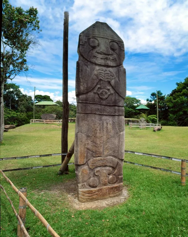 Vista por su cara frontal, la estatua de “El Obispo” muestra en realidad una escena de fecundación con tres figuras. La superior, semejante a otra estatua que se hallaba detrás de la gran cabeza monolítica que se divisa a la izquierda y hoy está en el bosque de las estatuas, es una representación solar, como la han interpretado varios arqueólogos. Tiene entre sus manos una pequeña figura con la cabeza hacia abajo, que no es otra cosa que el mono-serpiente, emblema de la estatuaria. Lo introduce en la vagina de la figura invertida del extremo inferior, que obviamente representa a la tierra. La escena, en síntesis, representa el momento de la inseminación de la tierra por el sol y sintetiza la transformación de las cosas y el culto a la fertilidad, tema central del arte del Macizo Colombiano.
