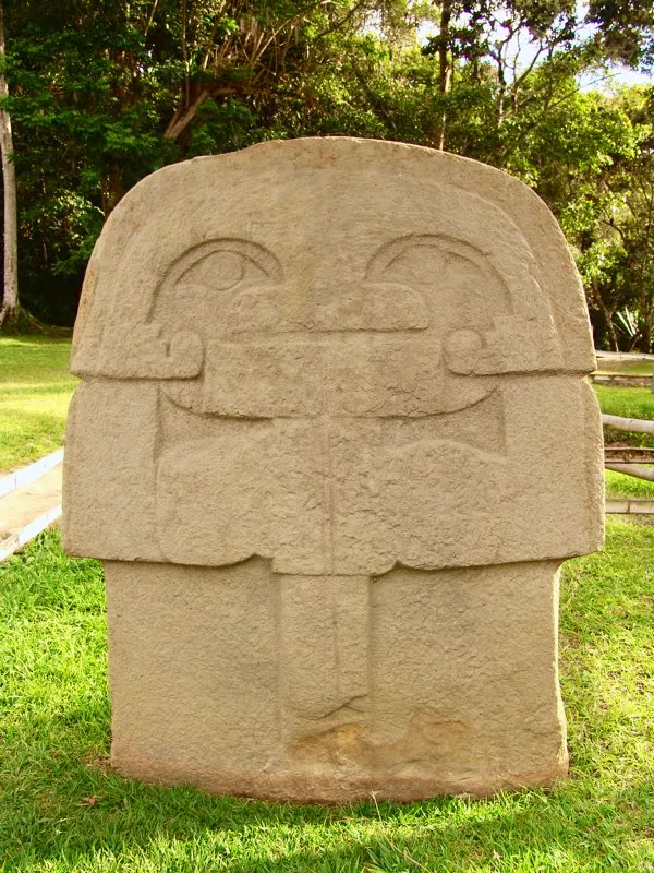 De las seis estatuas que Codazzi halló en la Mesita C del Parque Arqueológico de San Agustín, sitio que describió como “el cementerio de los sacerdotes, o tal vez el lugar de sus juntas para conferir la última enseñanza y el premio de la iniciación a los neófitos”. Sin duda son estatuas muy singulares, labradas algunas de ellas en relieve bidimensional para acentuar su carácter ultramundano, y en todos los casos con características especiales que las distinguen de las demás de la estatuaria. La figura cubre su rostro con una máscara sostenida por una vara.