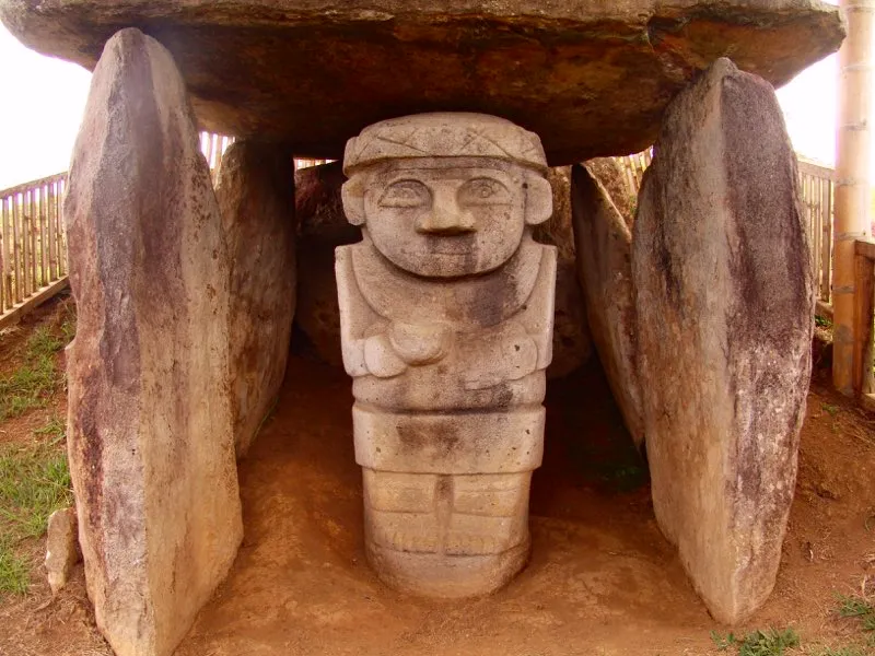 Imagen femenina con un cuenco o tazón, del Montículo X de la Mesta A del Alto de los Ídolos en Isnos. La vasija, sostenida con la mano derecha, en una regla invariable de la estatuaria cuando se trata de un solo objeto, posiblemente estaba destinada a contener una sustancia alucinógena, y por lo tanto es atributo chamanístico. Aún presenta rastros de pintura negra y carmelita en el rostro y los adornos.