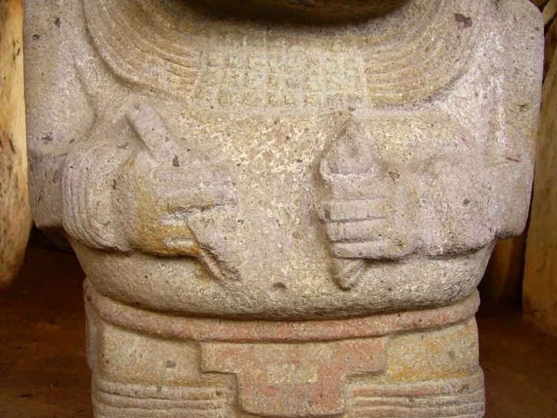 Detalles de estatuas de personajes con los implementos para la masticación de hojas de coca, a saber, una varita, en la mano derecha, y en la izquierda un recipiente que guarda cal, que adherida a la varita se lleva a la boca para la extracción de los alcaloides de la coca. El recipiente es usualmente un calabazo, o un caracol en la estatuaria, como los que llevan las figuras del Alto de los Ídolos.