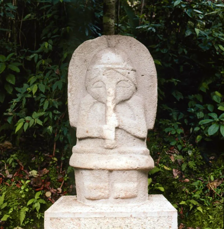 Procedente de El Cabuyal, esta estatua femenina ha suscitado toda clase de especulaciones desde cuando la describió Agustín Codazzi por primera vez en 1857. El largo objeto cilíndrico que se desprende de la nariz se ha confundido con la trompa de un elefante, impresión que parece reforzar el elemento en forma de herradura que circunda la parte superior de su cuerpo y que semeja las orejas de aquel animal. El objeto cilíndrico tiene un valor representativo doble. Es una trompeta, similar a las que se han hallado en otras regiones arqueológicas de Colombia, y a la vez es la trompa de un mamífero, pero no un elefante sino un tapir o danta. Trompeta y tapir se encuentran relacionados en un mito de origen conocido como “complejo del Yuruparí”, extendido por la cuenca amazónica y que advierte sobre los peligros de la exogamia.
