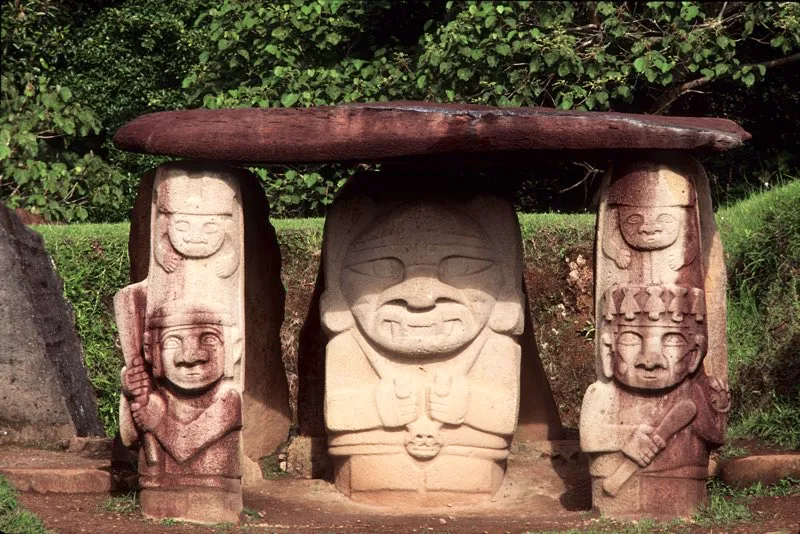 Vista frontal del Montículo Noroeste de la Mesita B del Parque Arqueológico de San Agustín. La estatua principal tiene como atributo lo que se conoce como “cráneo trofeo”, que llevó a describirla como “dios de la destrucción” o “deidad de la guerra”. Pero no obstante las estatuas que se encuentran en sus flancos y que tradicionalmente se han descrito como “guerreros”, no existe evidencia de que la guerra fuera una práctica común en el Macizo Colombiano, ni de que los pueblos que lo habitaron fueran conquistadores o hubieran sufrido asedios de pueblos enemigos. Además, los cráneos que muestran las seis estatuas que lo llevan —cuatro de ellas femeninas— son demasiado pequeños para ser humanos y más bien parecen de mono, lo cual confirmaría la hipótesis de que se trata de un simbolismo relacionado con los ancestros.