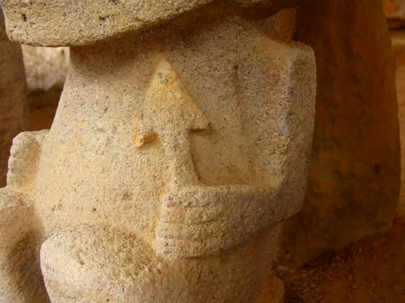 El objeto que lleva en la mano izquierda una estatua del Montículo I de la Meseta A del Alto de los Ídolos ha recibido una interpretación supuestamente muy obvia: es una flecha, y quien la porta es un guerrero. Sin embargo, en el arte del Macizo Colombiano nada es obvio. El triángulo que constituye la punta reproduce la forma de la cabeza de la mayoría de los monos de la estatuaria, e incluso de la gran cabeza de la Mesita B. Pero también se encuentra asociado con la serpiente y con el elemento femenino, como muestran los dibujos incisos de una piedra hallada en la Mesita B. Por lo tanto, la flecha no es otra cosa que la síntesis geométrica del mono-serpiente, y al parecer es un atributo exclusivamente femenino.