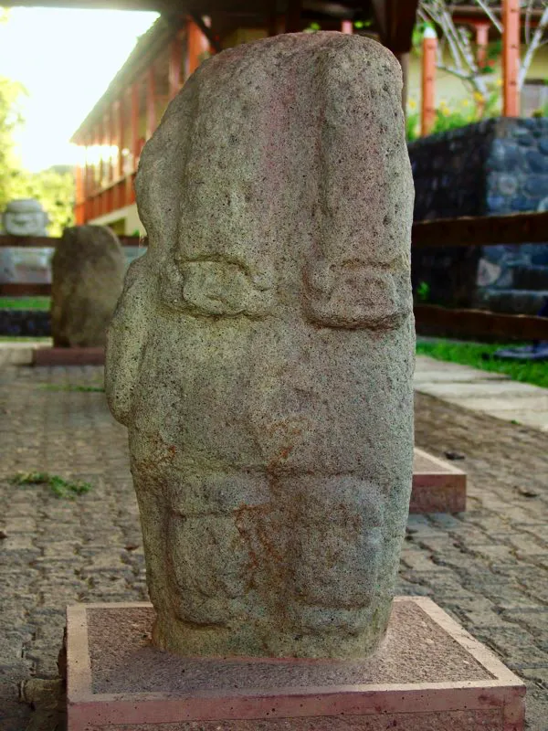 La identificación como síntesis geométrica del mono-serpiente de las cintas que descienden por la espalda de algunas estatuas queda demostrada por esta figura de procedencia desconocida. Claramente, las cintas terminan en dos cabezas, sin duda de mono. Dentro de la síntesis geométrica, las cabezas se reemplazan por borlas o cuadros de remate, como en la imagen del sol fecundando la tierra de la Mesita B.
